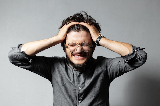 Portrait de jeune mec hurlant barbu aux cheveux et lunettes ébouriffés