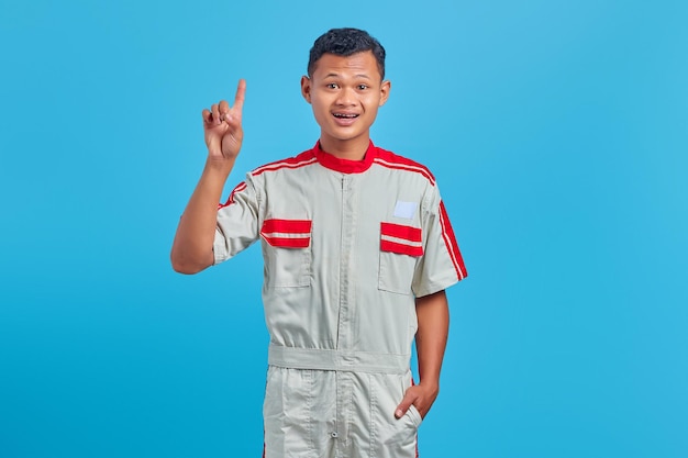 Portrait d'un jeune mécanicien excité ayant une idée créative et regardant la caméra sur fond bleu