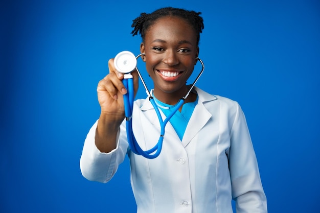 Portrait d'une jeune médecin africaine dans un studio bleu