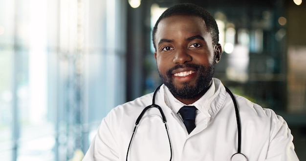 Portrait de jeune médecin afro-américain avec stéthoscope regardant la caméra et souriant joyeusement. Beau sourire de médecin de sexe masculin. Medic en robe blanche. À l'intérieur.