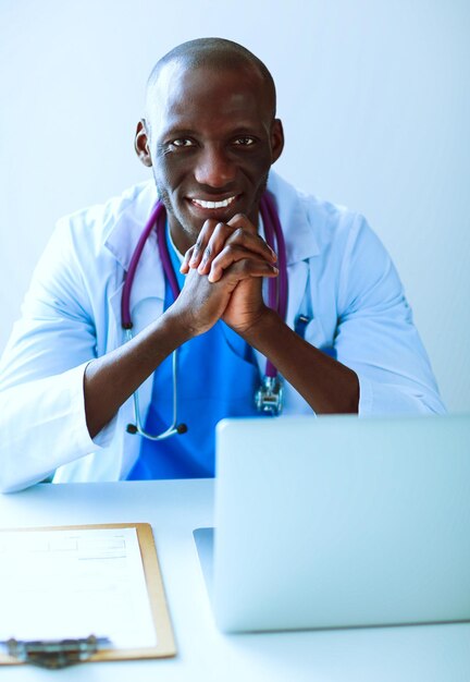 Portrait d'un jeune médecin de sexe masculin portant un casque tout en utilisant un ordinateur au bureau dans une clinique