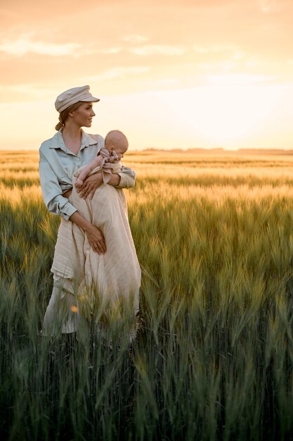 Un portrait de jeune mère avec un bébé dans ses bras au coucher du soleil dans le concept de famille heureuse sur le terrain