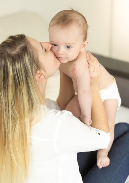 Portrait d'une jeune mère heureuse tenant son bébé et l'embrassant dans la joue