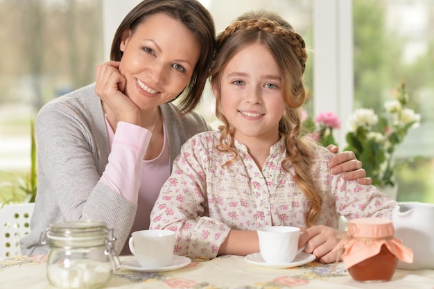 Portrait de jeune mère et sa fille buvant du thé à la maison