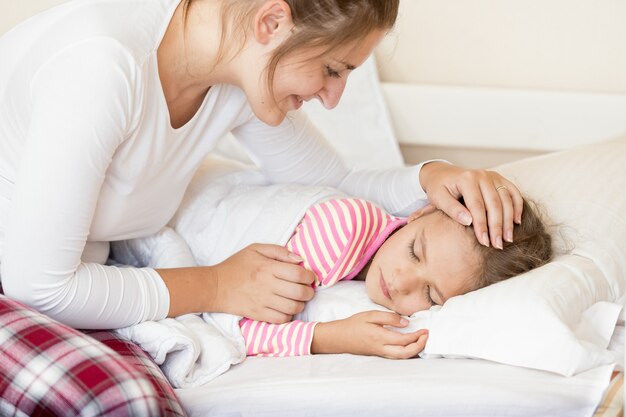 Portrait de jeune mère souriante tenant la main sur la tête des filles endormies