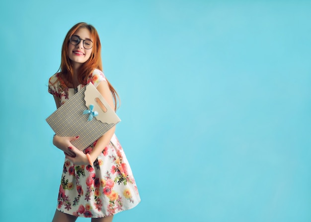 Portrait d'un jeune modèle féminin de race blanche dans des verres dans une robe blanche sur bleu