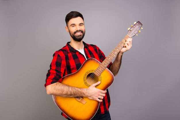 Portrait de jeune musicien à succès tenant la guitare et souriant