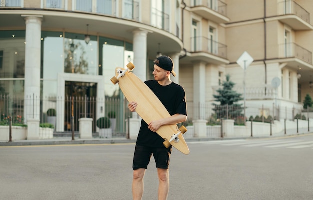 Portrait de jeune patineur avec longboards sur la rue de la ville