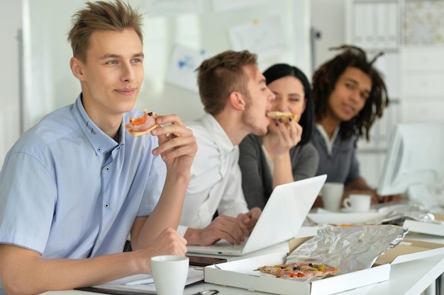 Portrait d'un jeune en pause manger de la pizza