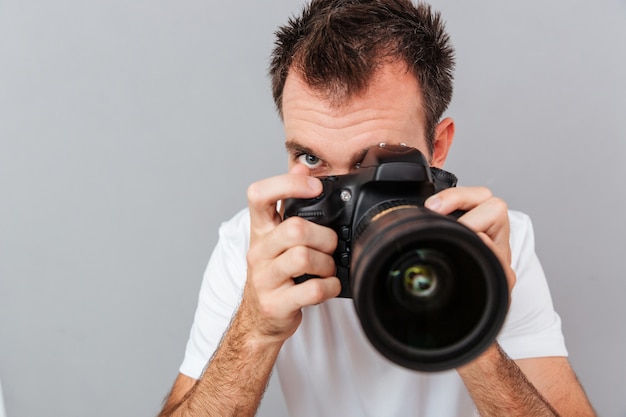 Portrait d'un jeune photographe avec appareil photo isolé sur fond gris