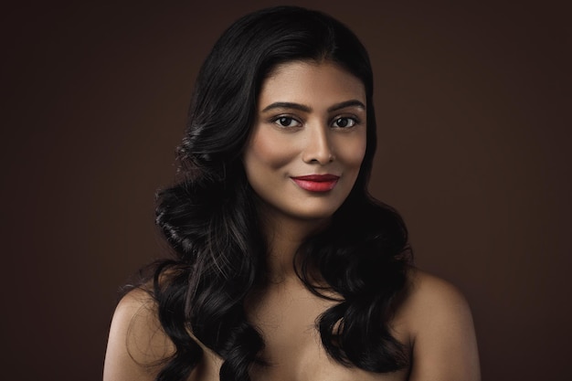 Portrait de jeune et riche femme indienne avec beau maquillage et coiffure sur fond marron