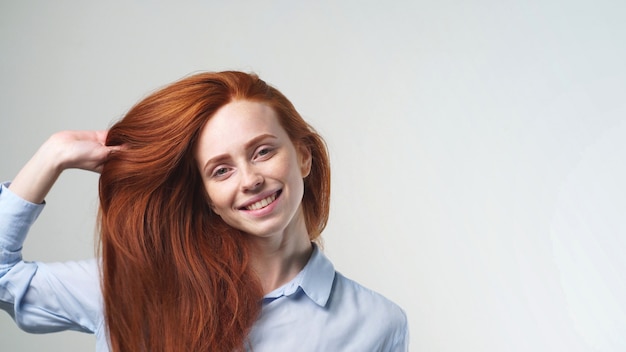 Portrait d'une jeune rousse heureuse émotionnelle, souriant à la caméra sur un fond isolé