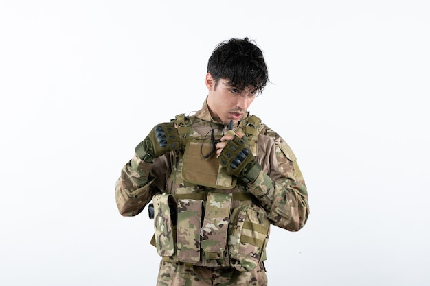 Portrait de jeune soldat en uniforme militaire sur mur blanc