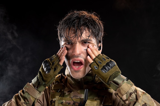 Portrait de jeune soldat en uniforme sur le mur sombre