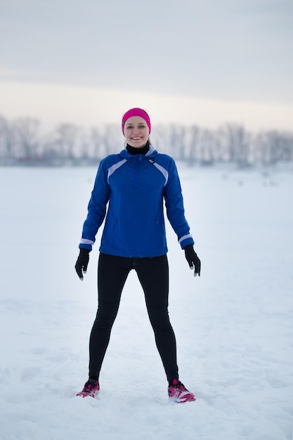 Portrait d'une jeune sportive féminine souriante dans un champ de glace d'hiver, concept de sport et de loisirs