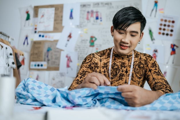 Portrait d'un jeune tailleur asiatique professionnel heureux avec un ruban à mesurer sur le cou travaillant