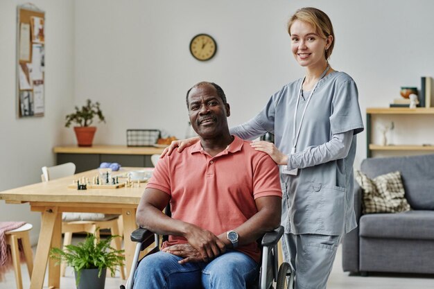 Portrait de jeune volontaire avec un homme âgé debout dans la salle et souriant à la caméra