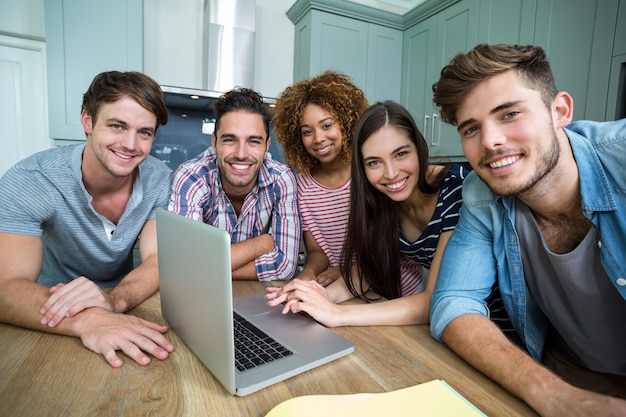 Portrait de jeunes amis souriant tout en utilisant un ordinateur portable