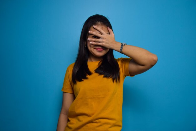 Portrait de jeunes belles femmes asiatiques avec un fond bleu isolé couvrant le geste des yeux