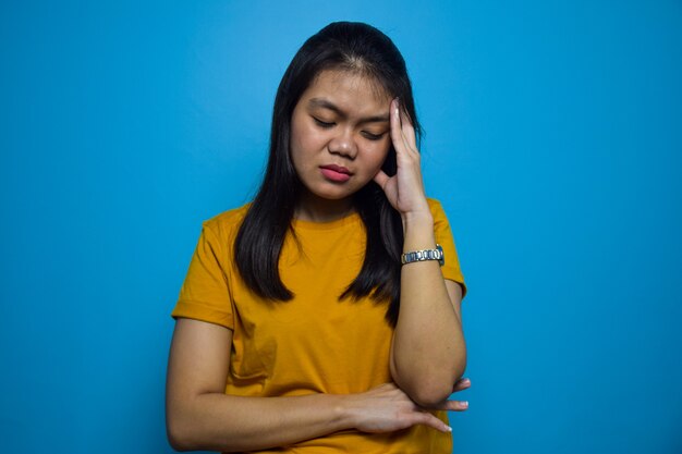 Portrait de jeunes belles femmes asiatiques avec un geste de mal de tête bleu fond isolé