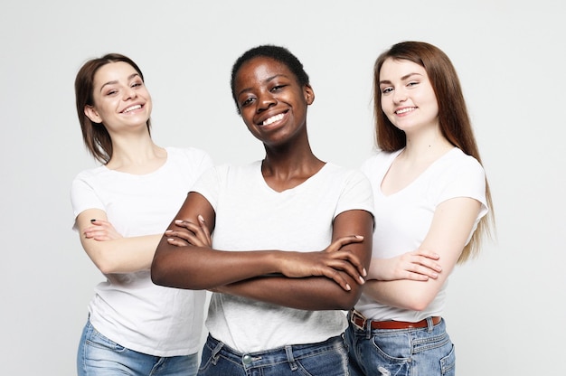 Portrait de jeunes femmes multiraciales debout ensemble et souriant à la caméra isolée sur fond blanc