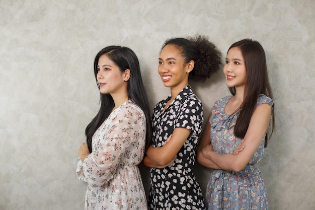 Portrait de jeunes femmes multiraciales debout ensemble et souriant à la caméra isolée sur fond de mur