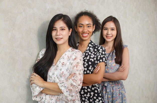 Portrait de jeunes femmes multiraciales debout ensemble et souriant à la caméra isolée sur fond de mur