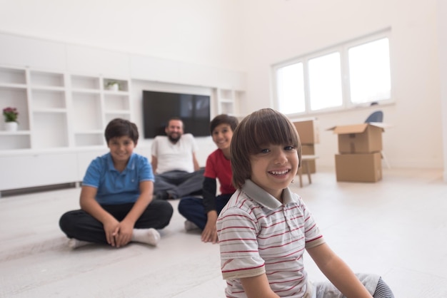 portrait de jeunes garçons heureux avec leur père assis sur le sol dans une nouvelle maison moderne