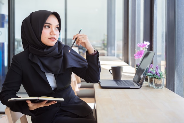 Portrait de jeunes gens d'affaires musulmans portant le hijab noir, travaillant au café.