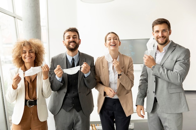 Portrait de jeunes gens d'affaires qui décollent leurs masques de protection au bureau