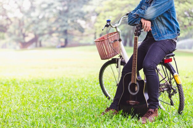 Portrait de jeunes hommes asiatiques assis à vélo jouent de la guitare