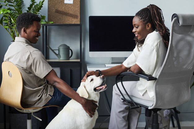 Portrait De Jeunes Souriants Caressant Un Chien Tout En Travaillant Dans Un Espace De Copie De Bureau Adapté Aux Animaux De Compagnie