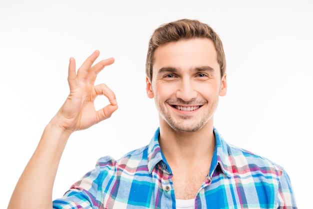 Portrait d'un joli beau jeune homme faisant des gestes ok