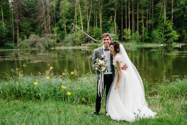 Portrait d'un joli marié et mariée debout sur la nature dans le parc