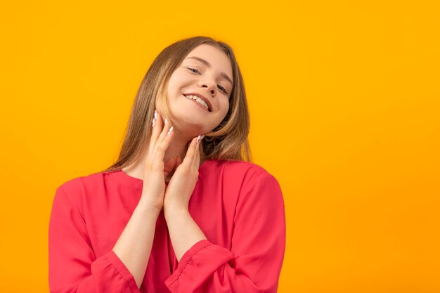 Portrait d'une jolie adolescente garde les mains près du visage et regarde dans l'appareil photo