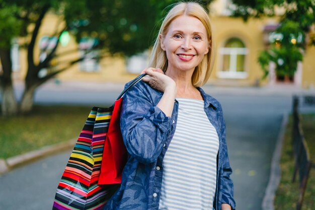 Portrait d'une jolie blonde tenant des sacs à provisions à l'extérieur dans la rue de la ville