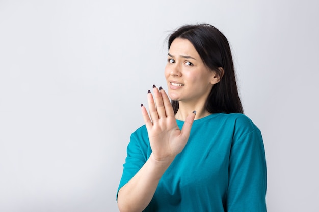 Portrait d'une jolie brune mal à l'aise, levant les paumes en geste d'arrêt. Cela suffit, merci.