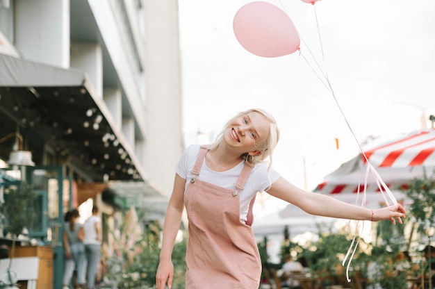 Portrait d'une jolie dame marchant dans la rue avec des ballons