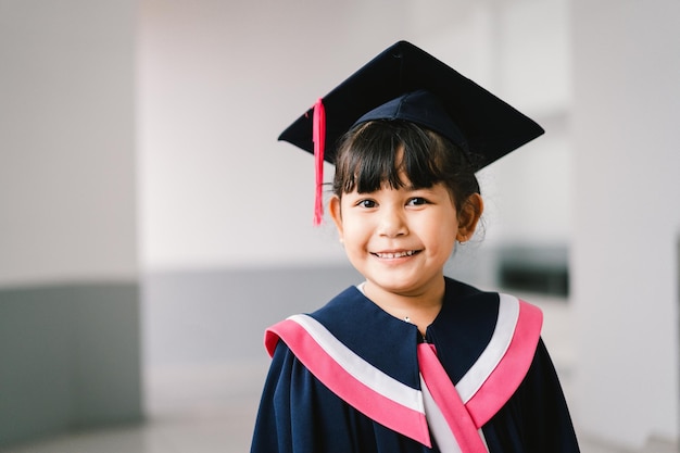 Portrait d'une jolie écolière diplômée asiatique avec robe de graduation à l'école