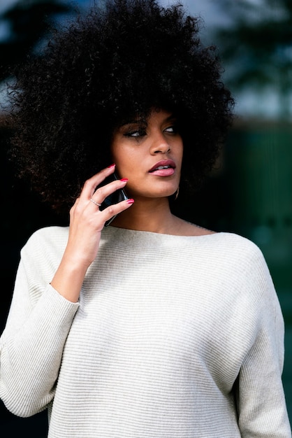 Portrait de jolie femme afro à l'aide de téléphone portable dans la rue. Concept de femme d & # 39; affaires