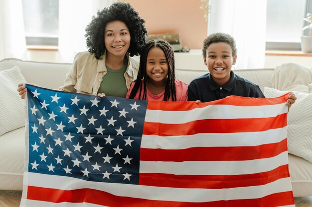 Portrait d'une jolie femme afro-américaine et d'enfants tenant le drapeau américain