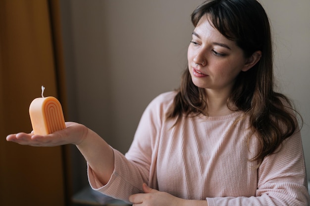 Portrait d'une jolie femme artisan qui tient en main une bougie terminée après le processus de création