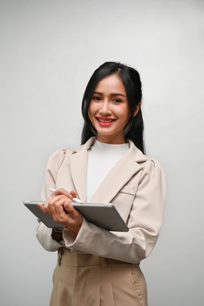 Portrait Une jolie femme asiatique ou une femme d'affaires se tient avec sa tablette sur un fond gris