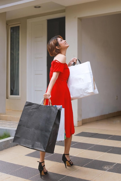 Portrait d'une jolie femme asiatique heureuse portant une robe tenant des sacs à provisions