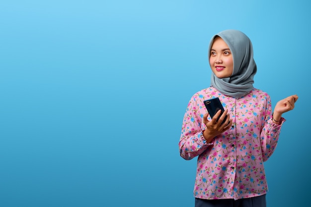 Portrait de jolie femme asiatique tenant un smartphone avec un sourire heureux et regardant de côté