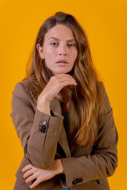 Portrait de jolie femme aux yeux bleus sur fond jaune dans une veste marron