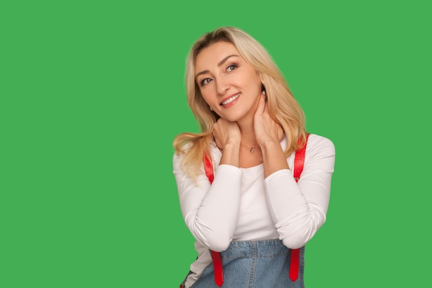 Portrait d'une jolie femme blonde adulte rêvant et souriant en pensant à d'agréables souvenirs heureux avec un visage méditatif paisible ayant des fantasmes studio d'intérieur tourné isolé sur fond vert