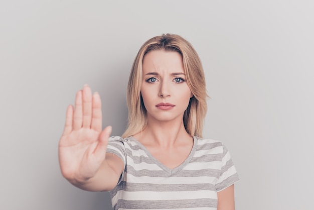 Portrait de jolie femme blonde faisant le geste d'arrêt