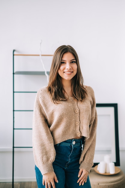 Photo portrait de jolie femme caucasienne heureuse avec des cheveux brune dans un salon lumineux