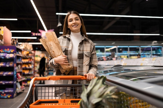 Portrait de jolie femme avec un chariot d'épicerie pendant le shopping